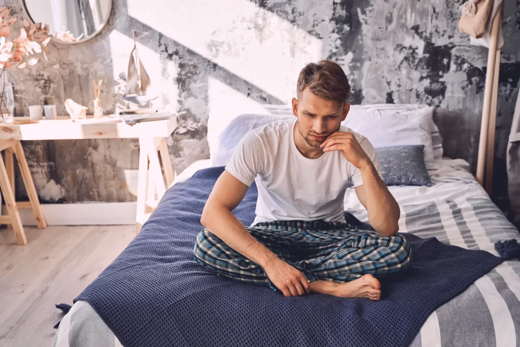 negative delighted young man sitting on the bed utc