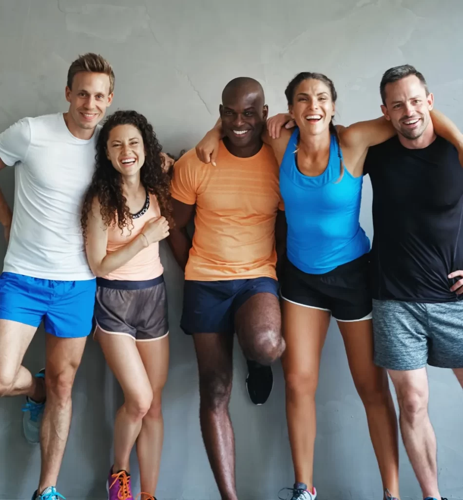 smiling friends in sportswear standing together in utc